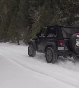 2WD JEEP Wrangler drives on a snowy road